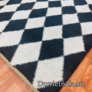 May include: Black and white diamond patterned rug with a jute border. The rug is made of woven cotton and is perfect for adding a touch of modern style to any room. The rug is handmade and features a unique design that is sure to make a statement.