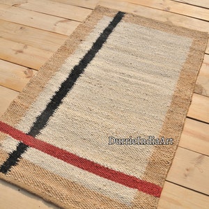 May include: A rectangular jute rug with a white background and black and red stripes. The rug has a natural jute border.