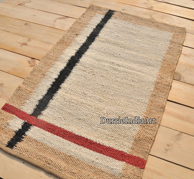 May include: A rectangular jute rug with a white background and black and red stripes. The rug has a natural jute border.