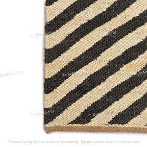 May include: A black and cream striped jute rug with a diagonal pattern. The rug is made of natural fibers and has a rustic look.