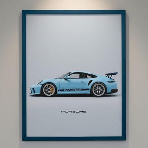 Puede incluir: Impresión enmarcada de un Porsche GT3 RS azul claro. El coche se muestra de perfil, destacando su diseño y características. La palabra "PORSCHE" está impresa en negro en la parte inferior. El marco es azul oscuro.