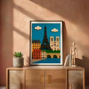 May include: A framed art print depicting a stylized cityscape of Paris, featuring the Eiffel Tower, Notre Dame Cathedral, and colorful buildings. The artwork is set against a blue sky with white clouds. The print is displayed on a wooden cabinet.