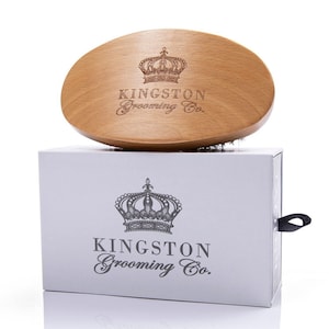May include: A wooden hair brush with a crown logo and the text "Kingston Grooming Co.". The brush is in a white box with a black pull tab.