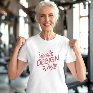 May include: A white t-shirt with the text "Your DESIGN here" in red lettering. The shirt is being worn by a person with gray hair.
