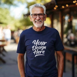 Könnte beinhalten: Ein marineblaues T-Shirt mit dem Text "Your Design Here" in weißer Schrift. Das T-Shirt wird von einer Person mit grauem Haar und Brille getragen, die sich im Freien aufhält.
