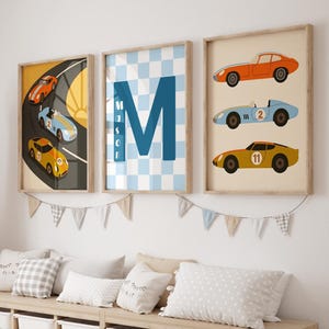 May include: Three framed wall art prints featuring race cars and the letter M with the name Mason. The left print shows cars on a track, the center has a blue checkered pattern with the letter M, and the right shows three stacked race cars.