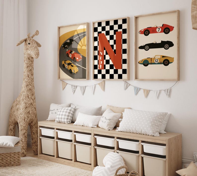 May include: Three framed prints featuring race cars and a checkered flag design. The prints are in neutral tones, with pops of red, black, and yellow. The artwork is displayed above a storage bench with white bins, creating a playful and stylish room.