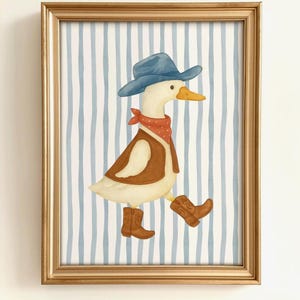 May include: A framed watercolor print features a duck dressed as a cowboy. The duck wears a blue hat, red bandana, brown vest, and cowboy boots. The background has blue and white vertical stripes, and the frame is gold.