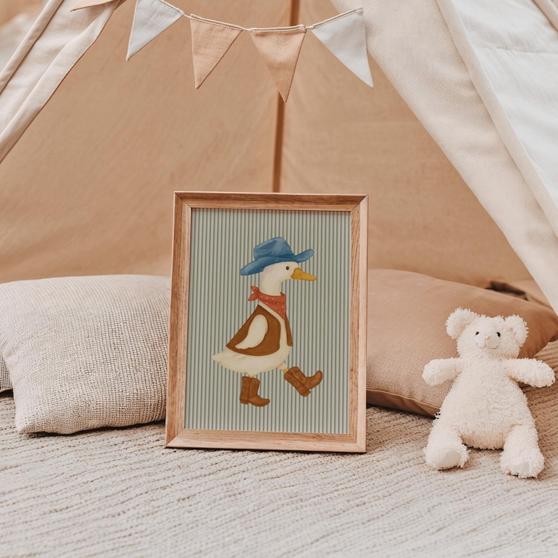 May include: A framed illustration of a cartoon duck wearing a blue cowboy hat, red bandana, brown vest, and boots. The background features a light blue and white striped pattern. The frame is made of wood.