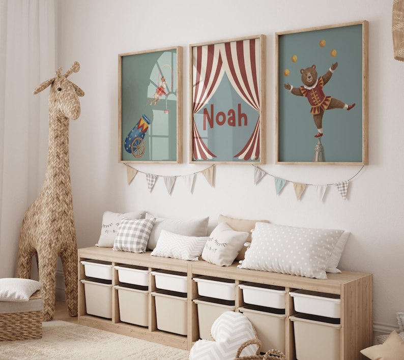 Puede incluir: Tres impresiones art&iacute;sticas enmarcadas con tem&aacute;tica de circo con una escultura de jirafa y un banco de almacenamiento. Las impresiones presentan un ca&ntilde;&oacute;n, una carpa de circo con el nombre "Noah" y un oso malabarista. El banco tiene contenedores de almacenamiento blancos.