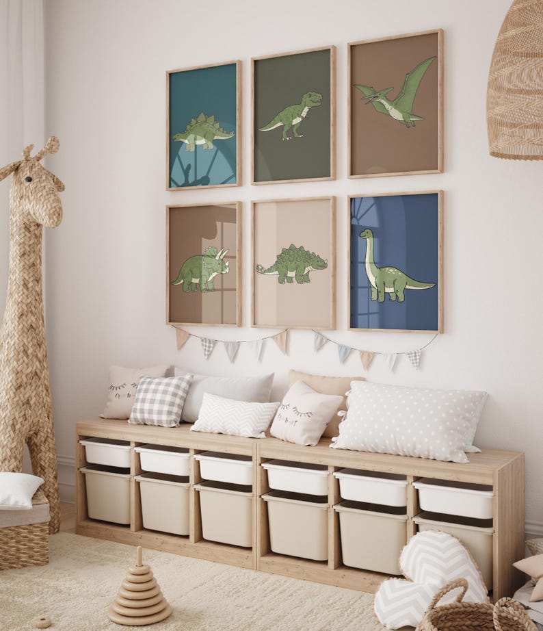 May include: A collection of six framed dinosaur art prints in a child's room. Each print features a different dinosaur illustration in green on a colored background. The room also includes a wooden storage bench with white bins, pillows, and a giraffe-shaped toy.