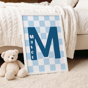 May include: A rectangular white-framed wall art print featuring a large dark blue letter M centered over a light blue and white checkered background. The name Mason is printed vertically in white capital letters inside the left leg of the M.