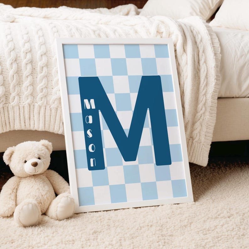 May include: A rectangular white-framed wall art print featuring a large dark blue letter M centered over a light blue and white checkered background. The name Mason is printed vertically in white capital letters inside the left leg of the M.