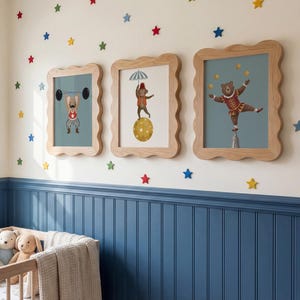 Puede incluir: Tres impresiones enmarcadas de animales de circo con marcos de madera festoneados cuelgan de una pared crema decorada con calcoman&iacute;as en forma de estrella de colores. Las impresiones presentan un perro levantando pesas, un oso sobre una bola y un oso haciendo equilibrio sobre un pedestal.