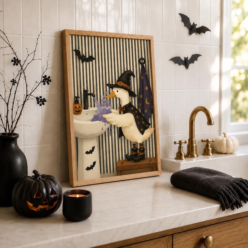 May include: A framed wall art print featuring a white duck wearing a black witch hat and cape, standing on a wooden crate to wash its wings in a pedestal sink. The background has black and white vertical stripes with bat silhouettes.