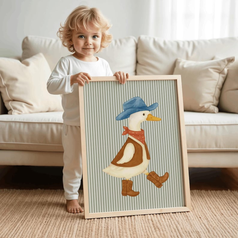 May include: A framed print featuring a whimsical illustration of a duck dressed as a cowboy. The duck wears a blue hat, red bandana, brown vest, and cowboy boots. The background has vertical stripes in light green and white.