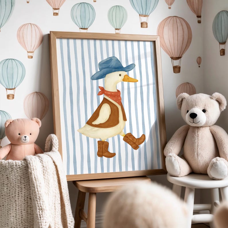 May include: A framed print featuring a watercolor illustration of a duck dressed as a cowboy, wearing a blue hat, red bandana, and brown vest and boots. The background has blue and white vertical stripes. The room is decorated with hot air balloon wall decals.