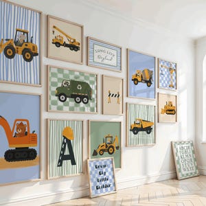 Könnte beinhalten: Eine Galeriewand mit gerahmten Kunstdrucken, die Baufahrzeuge, Tiere und Typografie zeigen. Die Sammlung umfasst Illustrationen von Baggern, Muldenkippern und Kränen sowie die Schriftzüge Long Live Boyhood und Dream Big Little Builder.