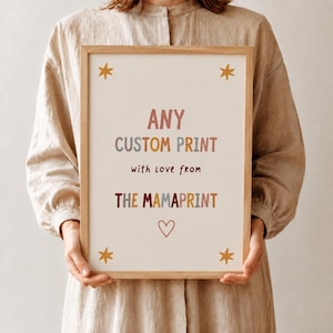 Pode incluir: Uma moldura de madeira retangular contendo uma impressão branca com o texto ANY CUSTOM PRINT with love from THE MAMAPRINT em letras multicoloridas, acentuada por quatro estrelas amarelas nos cantos e um pequeno coração rosa.