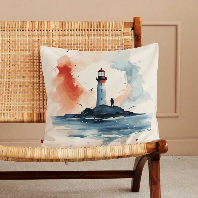 May include: A watercolour pillow featuring a lighthouse on a rocky island with a person standing on the rocks. The background is a soft blue and orange watercolour wash.