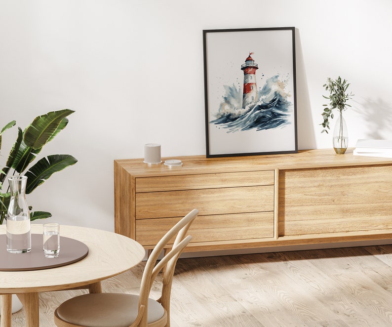 May include: A watercolour painting of a red and white lighthouse in a stormy sea. The painting is framed in black and hanging on a white wall above a wooden dresser.