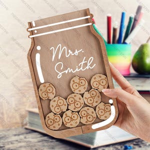 May include: Wooden jar-shaped sign with the text "Mrs. Smith" and a white border. The jar is filled with small wooden cookies with a bite taken out of them.