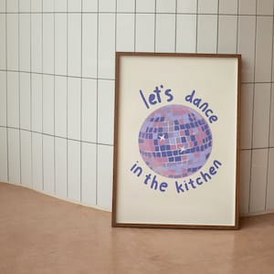 Puede incluir: Una impresión enmarcada con fondo blanco y una bola de discoteca morada y rosa con el texto "let's dance in the kitchen" en azul.