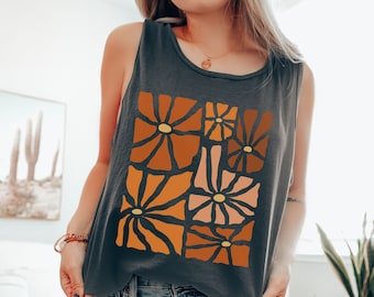 May include: A charcoal gray tank top with a graphic print of abstract orange and brown flowers. The tank top has a scoop neck and a relaxed fit.