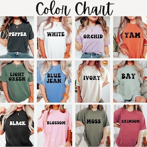 Op de afbeelding: Kleurenkaart met 12 verschillende T-shirt kleuren met de kleurnaam in wit op elk shirt gedrukt. De kleuren zijn: Pepper, Wit, Orchidee, Yam, Lichtgroen, Blauw Jeans, Ivoor, Baai, Zwart, Bloesem, Mos, en Koraalrood.