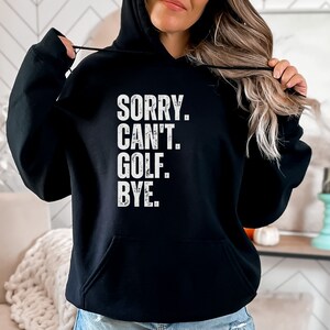 May include: Black hooded sweatshirt with the text "SORRY. CAN'T. GOLF. BYE." in white.