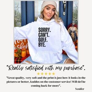 May include: White hooded sweatshirt with black text that reads "SORRY. CAN'T. GOLF. BYE."