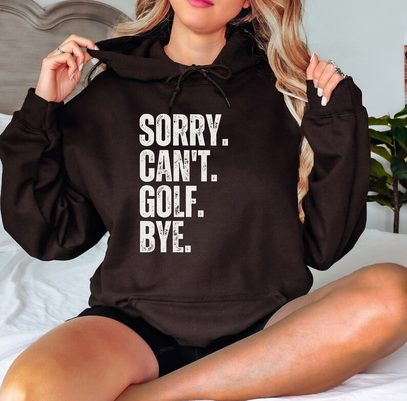 May include: A black hoodie with a white distressed graphic that reads "SORRY. CAN'T. GOLF. BYE."