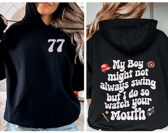 May include: Black hooded sweatshirt with a baseball-themed design. The front features the number "77" in white with a baseball stitch design. The back features the text "My Boy might not always swing but I do so watch your Mouth" in white with a baseball stitch design. The text is surrounded by baseball-themed graphics.