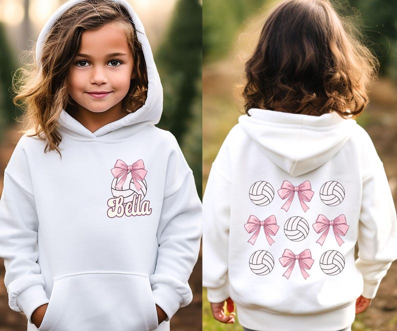 May include: White hooded sweatshirt with a volleyball and pink bow design. The text "Bella" is printed on the front of the sweatshirt.