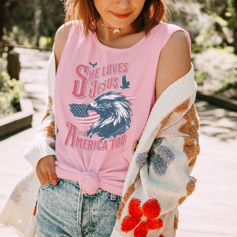 May include: A pink sleeveless tank top with a graphic of an eagle and an American flag. The graphic says "She Loves Jesus and America Too".