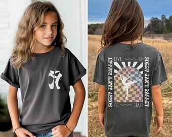 May include: A dark gray t-shirt with a white ballerina silhouette and the text "Sorry can't ballet" on the back. The text is repeated on the front of the shirt with a sun and moon graphic.