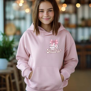May include: Pink hoodie with a white volleyball with a pink bow and the name Heather on it.