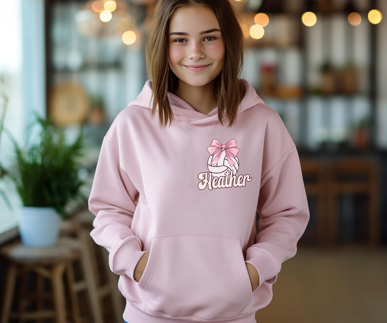 May include: Pink hoodie with a white volleyball with a pink bow and the name Heather on it.