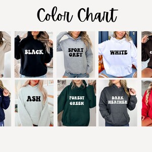 May include: Color chart showing 10 different hoodie colors: sand, black, sport grey, white, dark chocolate, navy, ash, forest green, dark heather, and red.