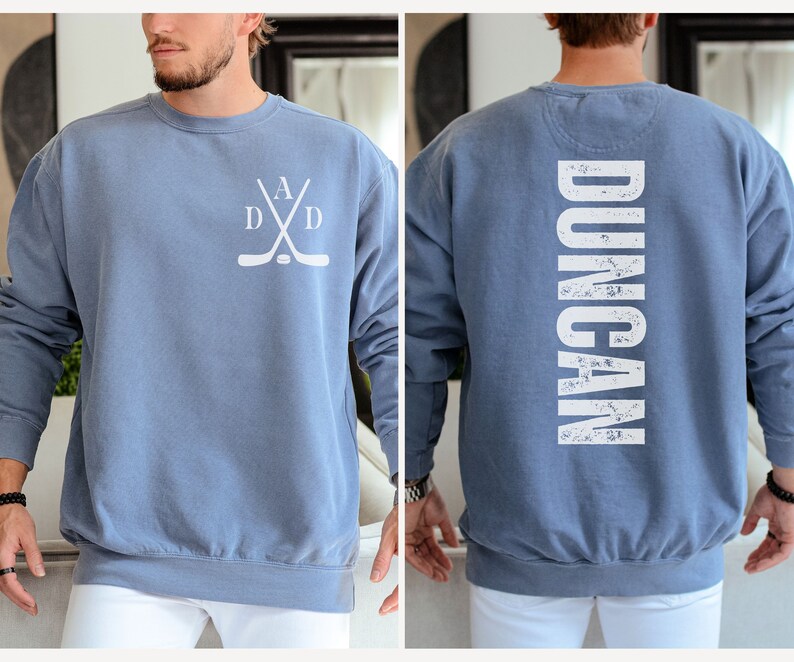 Puede incluir: Una sudadera azul con un dise&ntilde;o de palo de hockey blanco en la parte delantera y la palabra "DUNCAN" en blanco en la parte posterior.