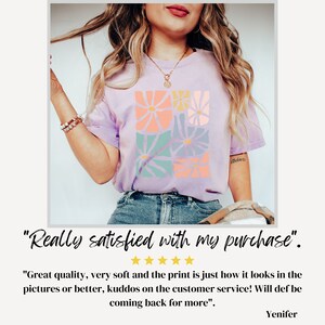 Op de afbeelding: Een vrouw draagt een lavendelkleurig T-shirt met een bloemenprint. Het shirt heeft een ronde hals en korte mouwen. De bloemenprint is in tinten roze, oranje, blauw en groen. "Really satisfied with my purchase." staat onder de afbeelding. "Great quality, very soft and the print is just how it looks in the pictures or better, kudos on the customer service! Will def be coming back for more." staat onder de quote. "Yenifer" staat onder de recensie.