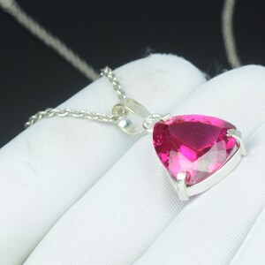Peut inclure: Un collier en argent avec un pendentif en forme de cœur, orné d'une pierre précieuse rose vif facettée. Le pendentif est serti dans un cadre en argent et suspendu à une fine chaîne en argent. La pierre a une taille brillante.