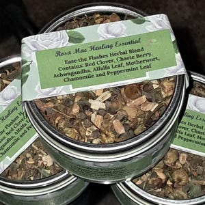 Puede incluir: Una lata de plata llena de una mezcla de hierbas secas, etiquetada "Rosa Mae Healing Essential Ease the Flashes Herbal Blend Contains: Red Clover, Chaste Berry, Ashwagandha, Alfalfa Leaf, Motherwort, Chamomile and Peppermint Leaf"