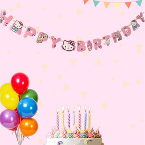 May include: A birthday celebration featuring a cake, balloons, and a banner. The white cake is decorated with colourful frosting and lit candles. A bunch of balloons in various colours is on the left. The banner reads "Happy Birthday" with cartoon characters.