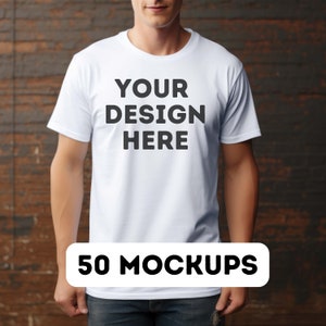 May include: A white t-shirt with the text "YOUR DESIGN HERE" printed on the front. The t-shirt is being worn by a person standing in front of a wooden background. 50 MOCKUPS.