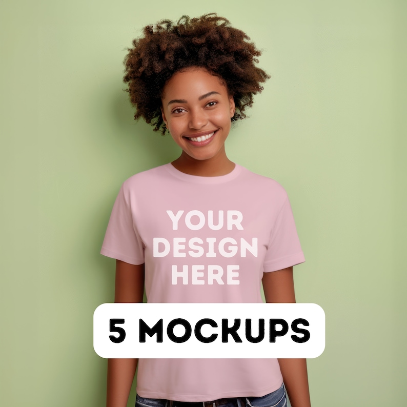May include: A woman wearing a pink t-shirt with the text "YOUR DESIGN HERE" printed on the front. The text is in white and is centered on the shirt. The woman is smiling and looking at the camera. 5 MOCKUPS is written in black text on a white rectangle.