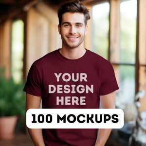 May include: A maroon t-shirt mockup with the text "YOUR DESIGN HERE" printed on the front. The text "100 MOCKUPS" is printed on a white rectangle below the shirt.