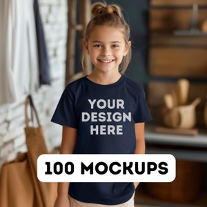 Pu&ograve; includere: Una maglietta blu navy con la scritta bianca "YOUR DESIGN HERE", indossata da una persona giovane. Un banner bianco in basso recita "100 MOCKUPS". Lo sfondo &egrave; sfocato. La persona sorride.