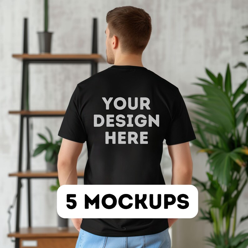 以下が含まれることがあります： 白い壁と棚と植物の前で立っている人の背中に「YOUR DESIGN HERE」と印刷された黒いTシャツのモックアップ。