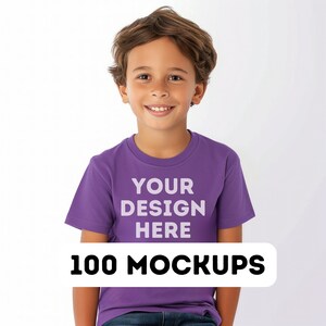 Pu&ograve; includere: Un bambino indossa una maglietta viola con la scritta bianca "YOUR DESIGN HERE". Sotto, un rettangolo bianco con le parole "100 MOCKUPS" in nero. Lo sfondo &egrave; bianco.